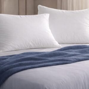 Snoozel duck feather pillows on a made bed with a navy throw